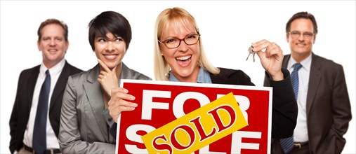 Real estate team behind with blonde woman in front holding keys and sold for sale real estate sign isolated on a white background