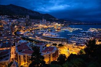 Aerial view of Monaco Monte Carlo harbour and illuminated city skyline in the evening blue hour twilight. Monaco Port night view with luxurious yachts