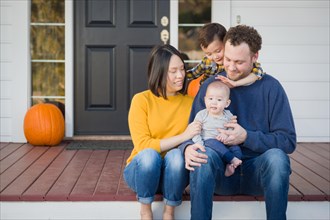 Young mixed-race chinese and caucasian family portrait on their front porch