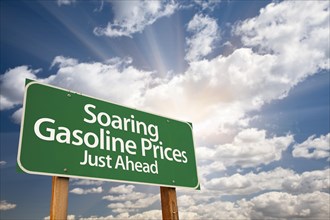 Soaring gasoline prices green road sign with dramatic clouds