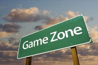 Game zone green road sign in front of dramatic clouds and sky