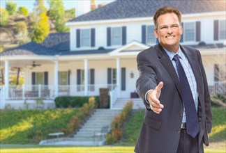 Smiling male agent reaching for hand shake in front of beautiful new house