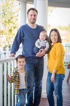 Young mixed-race chinese and caucasian family portrait on their front porch