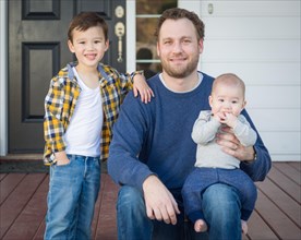 Young mixed-race father and sons on front porch