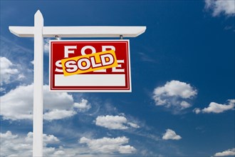 Right facing sold for sale real estate sign over blue sky and clouds with room for your text