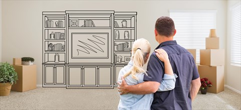 Couple inside empty room with moving boxes facing entertainment unit drawing on wall