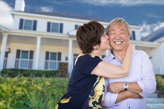 Happy chinese senior adult couple kissing in front of custom house