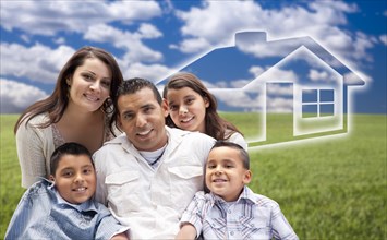Happy hispanic family portrait sitting in grass field with ghosted house figure behind