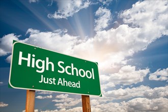 High school just ahead green road sign with dramatic clouds