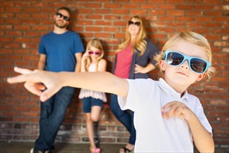 Cute young caucasian boy wearing sunglasses with family behind