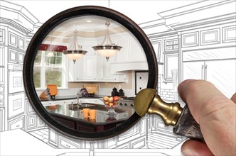 Hand holding magnifying glass revealing finished kitchen build over drawing