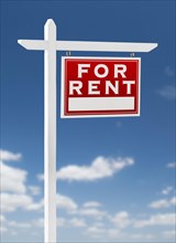 Right facing for rent real estate sign on a blue sky with clouds