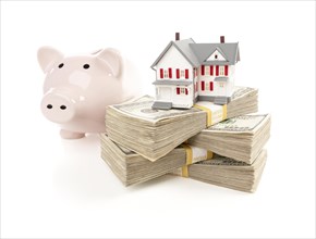Small house and piggy bank with stacks of hundred dollar bills isolated on a white background