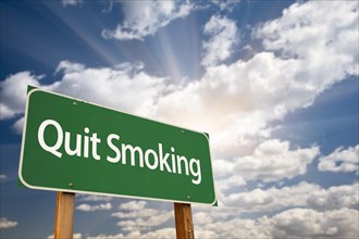 Quit smoking green road sign with dramatic clouds