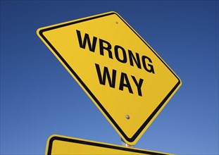 Yellow wrong way road sign against a deep blue sky with clipping path