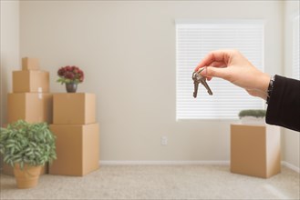 Woman handing over house keys in room with packed moving boxes
