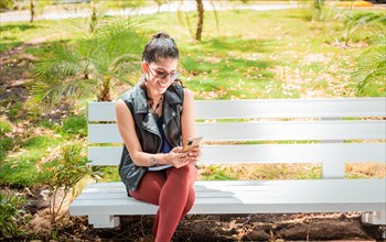 Girl sitting on a bench checking her cell phone