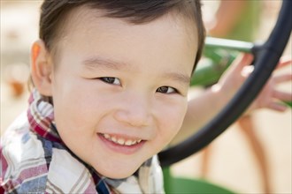 Adorable mixed-race young boy playing on the tractor at the pumpkin patch