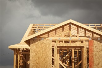 Home construction framing with ominous grey clouds behind