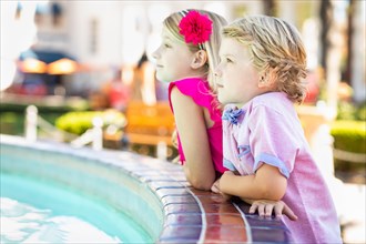 Cute young caucasian brother and sister enjoying the fountain at the park