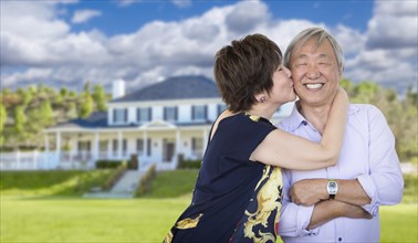 Attractive affectionate senior chinese couple in front of beautiful house