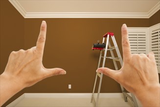 Hands framing brown painted room wall interior with ladder