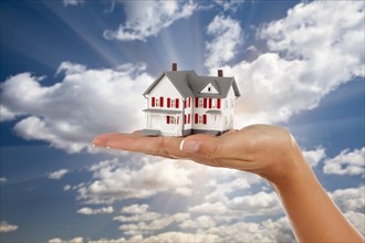 Model house in female hand on a cloud and sky background
