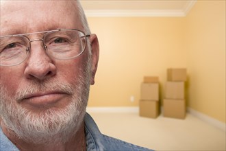 Sad older man in empty room with boxes