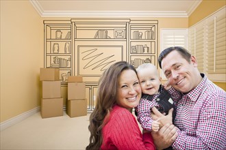Young family in room with moving boxes and drawing of entertainment unit on wall