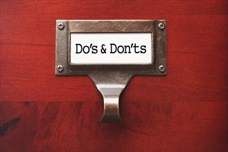 Lustrous wooden cabinet with do's and don'ts file label in dramatic light