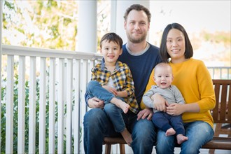 Young mixed-race chinese and caucasian family portrait on their front porch