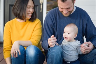 Young mixed-race chinese and caucasian family portrait on their front porch