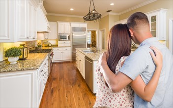 Young hopeful military couple looking at beautiful custom kitchen