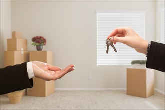 Woman handing over house keys in room with packed moving boxes