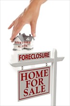 Womans hand choosing house with foreclosure home for sale real estate sign in front isolated on white