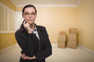 Attractive confident mixed-race woman in empty room with boxes