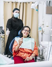 Dentist with thumb up patient in office