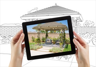 Female hands holding computer tablet with photo of pergola on screen