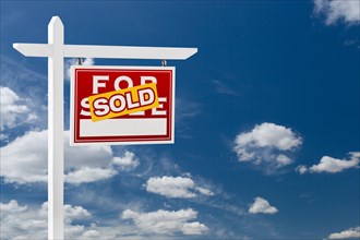 Right facing sold for sale real estate sign over blue sky and clouds with room for your text