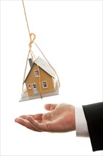 Businessman's hand under dangling house isolated on a white background