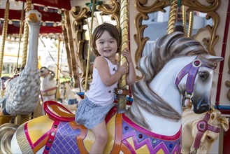 Happy girl riding the merry go round in San Diego