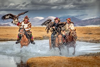 Eagle hunters crossing the small river. Western Mongolia