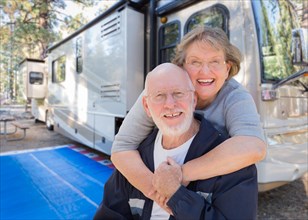 Senior couple in front of their beautiful RV at the campground