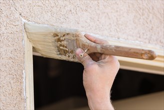 Professional painter cutting in with A brush to paint house door frame