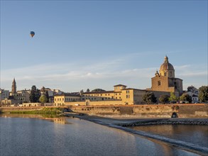 Hot air balloon flying over the Basilica di Santa Maria del Carmine on the river Arno
