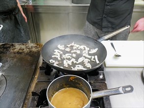 Chef cooking flambleing atlantic squid in a big pan in a professional kitchen. step by step gourmet seafood recipe. Professional gourmet cooking concept