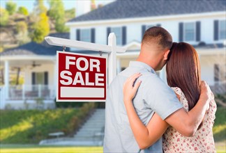 Military couple looking at house with for sale real estate sign in front