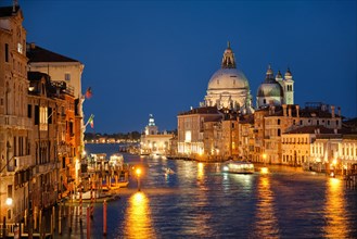View of Venice Grand Canal with boats and Santa Maria della Salute church in the evening from Ponte dell'Accademia bridge Venice