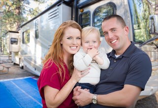 Happy young military family in front of their beautiful RV at the campground