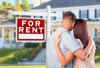 Military couple looking at house with for rent real estate sign in front